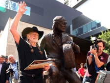 Country singer Willie Nelson waves during the unveiling of an eight-foot statue of himself on Friday, April 20, 2012 in Austin, Texas. The privately-funded monument near the new Moody Theater shows Nelson in a relaxed, standing pose and holding his guitar to the side, as if in conversation. (AP Photo/Austin American-Statesman, Jay Janner)
