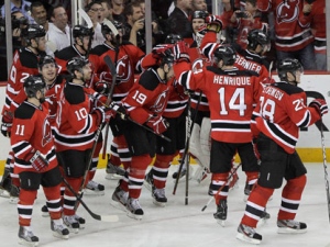 New Jersey Devils' Travis Zajac (19) is congratulated by teammates after his overtime goal in Game 6 of a first-round NHL hockey Stanley Cup playoff series against the Florida Panthers on Tuesday, April 24, 2012, in Newark, N.J. The Devils won 3-2, sending the series to a seventh game. (AP Photo/Julio Cortez)