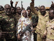 In this Tuesday, April 24, 2012 photo, Sudanese state Minister of Information Sana Hamad poses for a photo with Sudanese armed forces at the oil-rich border town of Heglig, Sudan. The African Union says Sudan must stop the aerial bombardment of South Sudan and has called on both countries to cease hostilities immediately. (AP Photo/Abd Raouf)