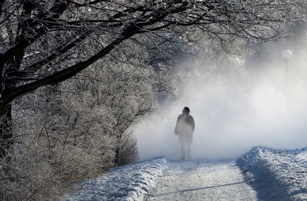 A pedestrian makes her way through a cloud of snow being created by a snowblower on the Rideau Canal Skate Way in Ottawa on Monday, Jan.5, 2015. For those suffering the post-holiday letdown - from being back to work, coping with frigid weather and facing looming credit-card bills at month's end - experts offer some tips for defeating the January blues. (Sean Kilpatrick /The Canadian Press)