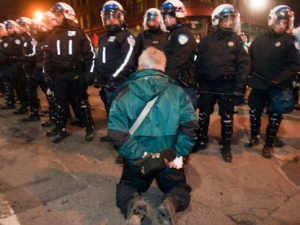 A man kneels in front of riot police as students protest against tuition fee hikes Friday, April 27, 2012 in Montreal.THE CANADIAN PRESS/Ryan Remiorz