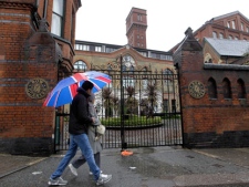 People walk past gated residential flats in Bow, east London, where the Ministry of Defence have warned residents that surface-to-air missiles could be stationed on their rooftops during the London Olympics, Sunday, April 29, 2012. (AP Photo/Sang Tan)