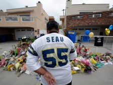 San Diego Chargers fan Jerry Lopez looks over a memorial set-up in the driveway of the house of former NFL star Junior Seau on Thursday, May 3, 2012, in Oceanside, Calif. Seau's apparent suicide stunned an entire city and saddened former teammates who recalled the former NFL star's ferocious tackles and habit of calling everybody around him "Buddy." (AP Photo/Denis Poroy)
