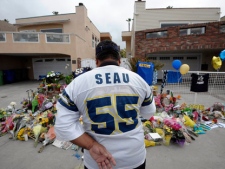 San Diego Chargers fan Jerry Lopez looks over a memorial set-up in the driveway of the house of former NFL star Junior Seau Thursday, May 3, 2012, in Oceanside, Calif. Seau's apparent suicide stunned an entire city and saddened former teammates who recalled the former NFL star's ferocious tackles and habit of calling everybody around him "Buddy." (AP Photo/Denis Poroy)
