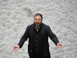 In this Monday, Oct. 11, 2010 file photo Chinese artist Ai Weiwei poses with some seeds from his art installation 'Sunflower Seeds' in London. (AP Photo/Lennart Preiss)