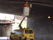 A city worker looks for loose concrete underneath the Gardiner Expressway Thursday afternoon. (CP24/Katie Simpson)