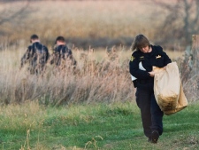 OPP officers walk out off deep brush with a bag of materials as police believe the body of 15-year-old Brandon Crisp may have been found by hunters just north of Barrie, Ont., on Wednesday, Nov. 5, 2008. (Nathan Denette / THE CANADIAN PRESS)