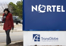 A reporter for 'A' News walks past the Nortel office tower sign in Etobicoke, west-end Toronto, on Monday, Nov. 10, 2008. (Nathan Denette / THE CANADIAN PRESS)