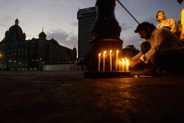 People light candles in front of the Taj Mahal hotel, background left, in Mumbai, India, Sunday, Dec. 7, 2008. (AP / Gautam Singh)