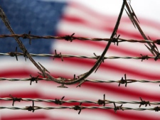 An American flag flies behind the barbed and razor-wire at the Camp Delta detention facility, at Guantanamo Bay U.S. Naval Base, Cuba. (AP / Brennan Linsley)