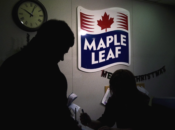 A Maple Leaf Foods employee, right, signs in a person from the media at the company's meat facility in Toronto on Monday, December, 15, 2008. (Nathan Denette / THE CANADIAN PRESS)