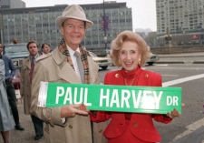 In this Nov. 16, 1988 file photo, radio commentator Paul Harvey and his wife, Lynn, hold a street sign bearing his name in Chicago. (AP / Charles Bennett)