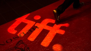 A man walks on a red carpet displaying a sign for the Toronto International Film Festival at the TIFF Bell Lightbox in Toronto on Sept. 3, 2014.  (Darren Calabrese / THE CANADIAN PRESS)
 