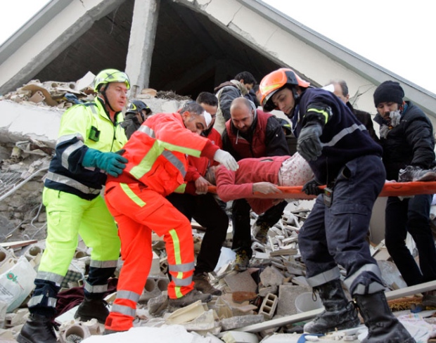 Firefighters carry a woman out of a crumbled home in the city of L'Aquila, after a strong earthquake rocked central Italy, early Monday, April 6, 2009.(AP / Pier Paolo Cito)