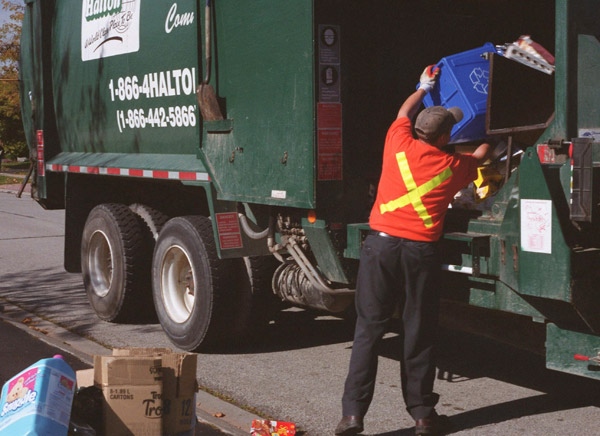 A worker empties materials into a recycling garbage truck in Oakville, Ont., Friday, Oct. 10, 2003. (Richard Buchan / THE CANADIAN PRESS)