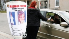 Tiffany Ackers hands out a poster for missing Victoria "Tori" Stafford, 8, on a street corner in Woodstock, Ont. on Friday April 10, 2009. THE CANADIAN PRESS/Dave Chidley