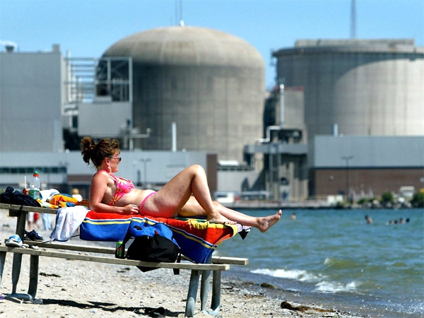 People bask in the sun next to the Pickering Nuclear Plant in Pickering, Ont., about 50 km east of Toronto. (CP / Kevin Frayer)