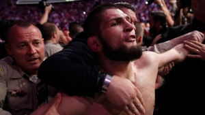 Khabib Nurmagomedov is held back outside of the cage after fighting Conor McGregor in a lightweight title mixed martial arts bout at UFC 229 in Las Vegas, Saturday, Oct. 6, 2018. Nurmagomedov won the fight by submission during the fourth round to retain the title. (AP Photo/John Locher)