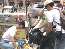 Toronto Centre MPP George Smitherman (green shirt) holds a garbage bag on Saturday, July 18, 2009 while another volunteer fills it up.