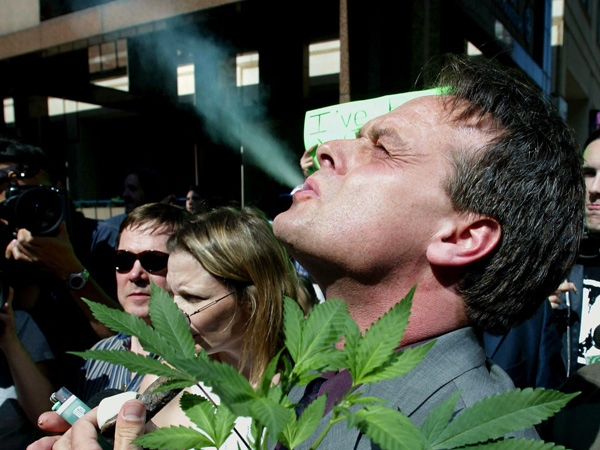 Cannabis crusader Marc Emery, of Vancouver, smokes marijuana as he holds a plant at a gathering of pro-marijuana legalization supporters outside police headquarters in Toronto June 19, 2003. (CP / Kevin Frayer)