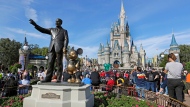 FILE - In this Jan. 9, 2019 photo, guests watch a show near a statue of Walt Disney and Micky Mouse in front of the Cinderella Castle at the Magic Kingdom at Walt Disney World in Lake Buena Vista, part of the Orlando area in Fla. Officials from SeaWorld and Disney World say they hope to open their theme parks in Orlando, Fla., in June and July. A city task force approved the plans on Wednesday, May 27, 2020. (AP Photo/John Raoux, File)