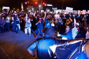 In this Tuesday, June 2, 2020 photo, protesters cheer as a Hampton police officer kneels with them along Mercury Boulevard in Hampton, Va., during a rally against police brutality sparked by the death of George Floyd, a black man who died after being restrained by Minneapolis police officers on May 25. ( Jonathon Gruenke/The Virginian-Pilot via AP)