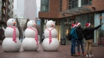 A group wearing Santa hats stop to take a selfie next to the snowmen display at the Distillery District in Toronto on Christmas Eve, Thursday, Dec. 24, 2020. THE CANADIAN PRESS/Tijana Martin