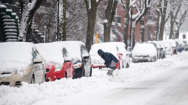 A person shovels snow from around a car during a snowstorm in Montreal, Saturday, January 16, 2021. THE CANADIAN PRESS/Graham Hughes
