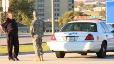 This still made from video shows a police officer and soldier blocking the road at the main gate of the Army base at Fort Hood, Texas on Thursday Nov. 5, 2009.  (AP / Richard Matthews)