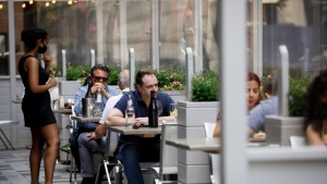 A waiter talks with patrons at a patio in Yorkville in Toronto, on Friday, June 26, 2020. THE CANADIAN PRESS/Cole Burston 