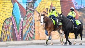 Police officers ride their horses past a mural on Earth Day during the COVID-19 pandemic in Toronto on Thursday, April 22, 2021. THE CANADIAN PRESS/Nathan Denette 