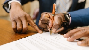 An individual signs a legal contract in this stock photo. (Pexels/RODNAE Productions)