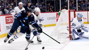 Winnipeg Jets' Jansen Harkins (12) and Toronto Maple Leafs' Justin Holl (3) skate after a loose puck during the second period of NHL action in Winnipeg, Sunday, Dec. 5, 2021. THE CANADIAN PRESS/Fred Greenslade