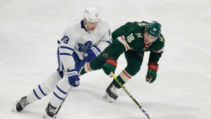 Toronto Maple Leafs center Jason Spezza (19) controls the puck in front of Minnesota Wild center Rem Pitlick (16) during the first period of an NHL hockey game, Saturday, Dec. 4, 2021, in St. Paul, Minn. (AP Photo/Andy Clayton-King) 