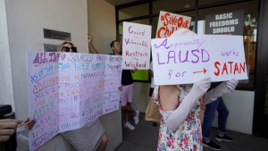 Anti-vaccine mandate protesters hold signs outside the front doors of the Los Angeles Unified School District, LAUSD headquarters in Los Angeles, on Sept. 9, 2021. New research indicates that far-right extremists and white supremacists are gaining new followers and new influence by co-opting conspiracy theories about COVID-19. (AP Photo/Damian Dovarganes, File)
