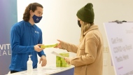 A woman receives a free COVID-19 rapid antigen test kit at a pop-up site in Toronto's Yorkdale Shopping Mall on Thursday, December 16, 2021. THE CANADIAN PRESS/Chris Young 