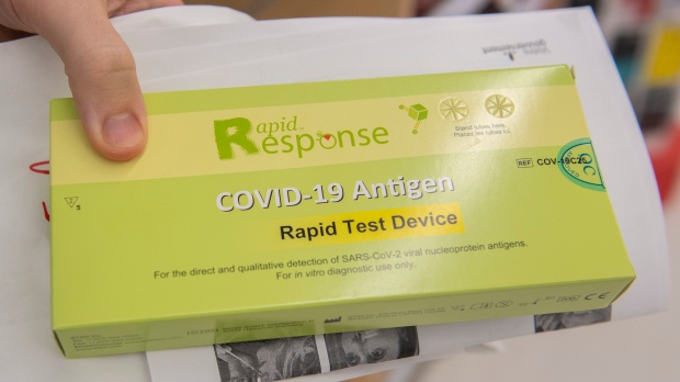 A man displays his COVID-19 rapid test kit after receiving it at a pharmacy on Monday, December 20, 2021. THE CANADIAN PRESS/Graham Hughes 