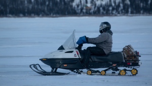 In a photo provided by the U.S. Marine Corps, U.S. Marine Corps Gunnery Sgt. Jake Paolucci rides a snow machine across the Noatak River while traveling from Noatak, Alaska, to Kotzebue, Alaska, Dec. 14, 2021. Marines on snowmobiles delivered toys to boys and girls in Alaska's Arctic. (Cpl. Brendan Mullin/U.S. Marine Corps via AP )