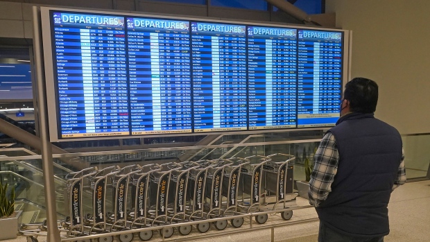 A man looks at the departures board at Salt Lake City International Airport Friday, Dec. 24, 2021, in Salt Lake City. At least three major airlines say they have canceled dozens of flights because illnesses largely tied to the omicron variant of COVID-19 have taken a toll on flight crew numbers during the busy holiday travel season.   (AP Photo/Rick Bowmer)