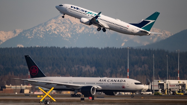 An Air Canada flight departing for Toronto, bottom, taxis to a runway as a WestJet flight bound for Palm Springs takes off at Vancouver International Airport, in Richmond, B.C., on Friday, March 20, 2020. THE CANADIAN PRESS/Darryl Dyck