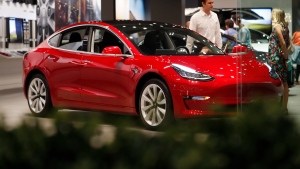 In this July 6, 2018, file photo, a prospective customer confer with sales associate as a Model 3 sits on display in a Tesla showroom in the Cherry Creek Mall in Denver.  (AP Photo/David Zalubowski, File) 
