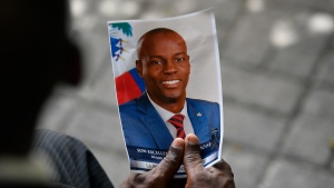 FILE - A person holds a photo of the late Haitian President Jovenel Moise during his memorial ceremony at the National Pantheon Museum in Port-au-Prince, Haiti, July 20, 2021. Haiti's National Police said Saturday, Jan. 15, 2022, that former Sen. John Joel Joseph, sought in the July 7 killing of Moise, has been arrested in Jamaica. (AP Photo/Matias Delacroix)