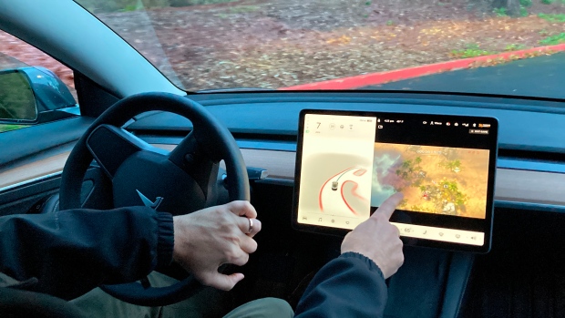 FILE - Vince Patton, a new Tesla owner, demonstrates on Dec. 8, 2021, on a closed course in Portland, Ore., how he can play video games on the vehicle's console while driving. (AP Photo/Gillian Flaccus, File) 