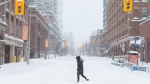 A person walks across a street in downtown Toronto as a heavy snowfall affects the greater Toronto area on Monday January 17, 2022. THE CANADIAN PRESS/Chris Young
