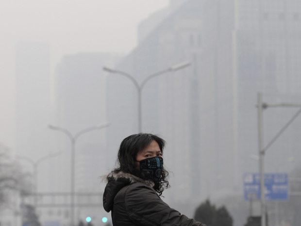 A masked woman looks away while crossing a street in the city centre shrouded in fog, caused by air pollution, in Beijing Monday, Dec. 7, 2009. Negotiators in Copenhagen are trying to set targets for controlling emissions of carbon dioxide and other global warming cases, including by the leading contributors, China and the United States. (AP / Andy Wong)