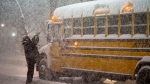 A school bus driver tries to clear snow as a winter storm causes the closure of schools in Toronto on Monday January 17, 2022. THE CANADIAN PRESS/Frank Gunn