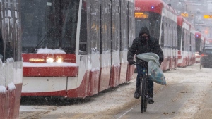 A cyclist makes his way past dozens of stranded streetcars during a severe winter storm in Toronto on Monday January 17, 2022. THE CANADIAN PRESS/Frank Gunn