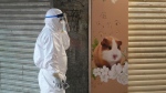 A staffer from the Agriculture, Fisheries and Conservation Department walks past a pet shop which was closed after some pet hamsters were, authorities said, tested positive for the coronavirus, in Hong Kong, Tuesday, Jan. 18, 2022. Hong Kong authorities said Tuesday that they will kill about 2,000 small animals, including hamsters, after several tested positive for the coronavirus at the pet store where an employee was also infected. (AP Photo/Kin Cheung) 