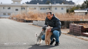 Yoichi Yatsuda plays with his dogs after moving back to his home in Futaba town of Fukushima prefecture, Japan, Thursday, Jan. 20, 2022. Several former residents of Futaba, including Yatsuda, the only remaining uninhabited town in Japan still recovering from effects of radiation from nuclear plant meltdowns in 2011, have returned to live for the first time since the massive earthquake and tsunami forced them out. (Kota Endo/Kyodo News via AP) 