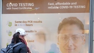 A woman walks past a poster of a COVID-19 testing center in Dublin, Wednesday Jan. 12, 2022. (Niall Carson/PA via AP) 